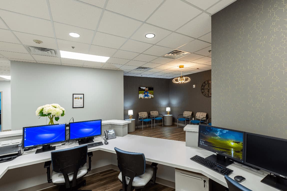 Completed reception and waiting area refresh with front desk workstations, seating, and updated commercial finishes.