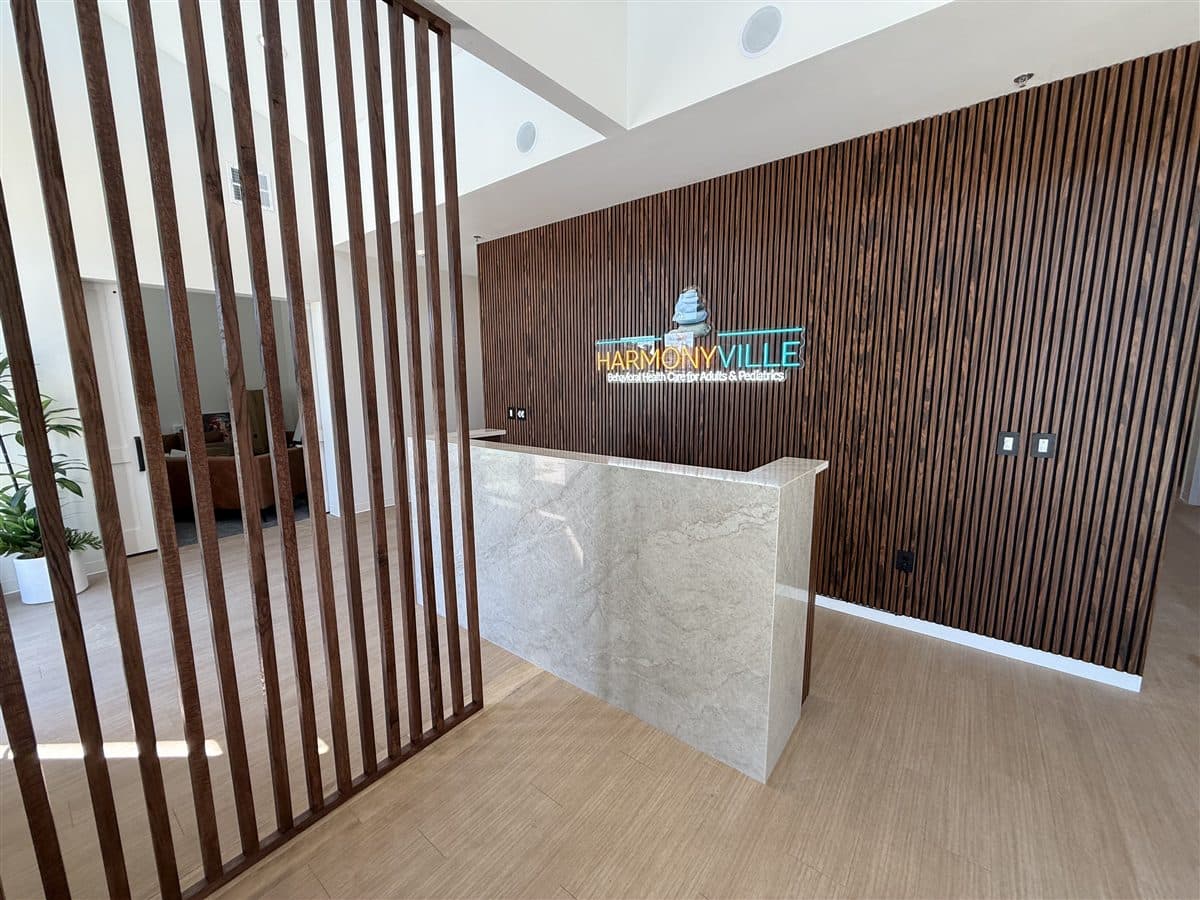 Completed office reception build-out by i30 Builders: stone-clad reception desk against a walnut slat feature wall with illuminated brand signage.