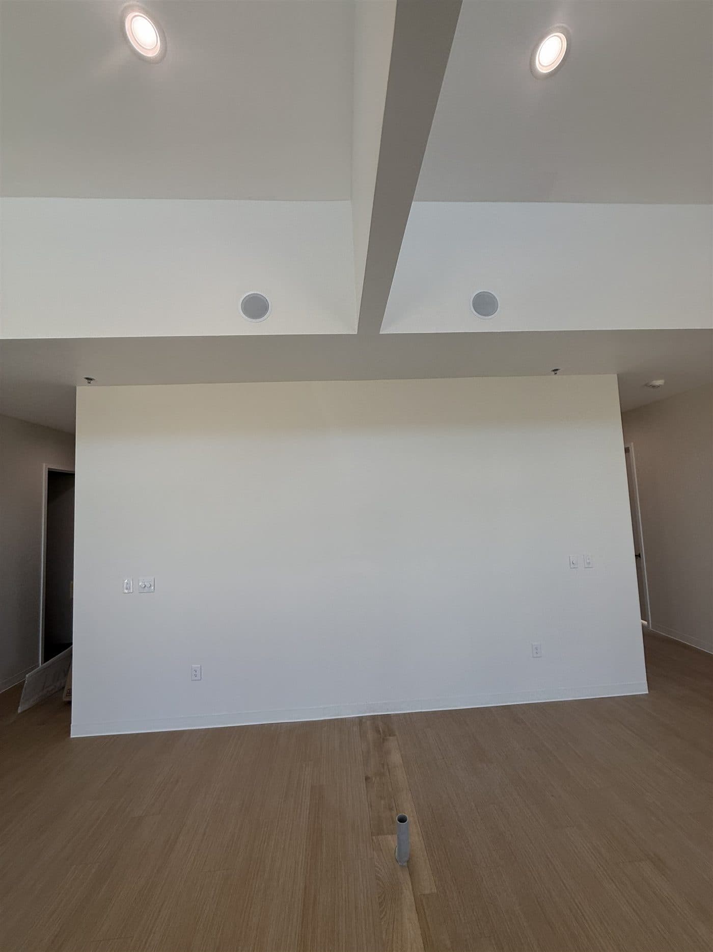 A raw white-box commercial shell before finish-out by i30 Builders: bare painted walls, new LVP flooring, recessed lighting, and stubbed utilities ready for a tenant build.