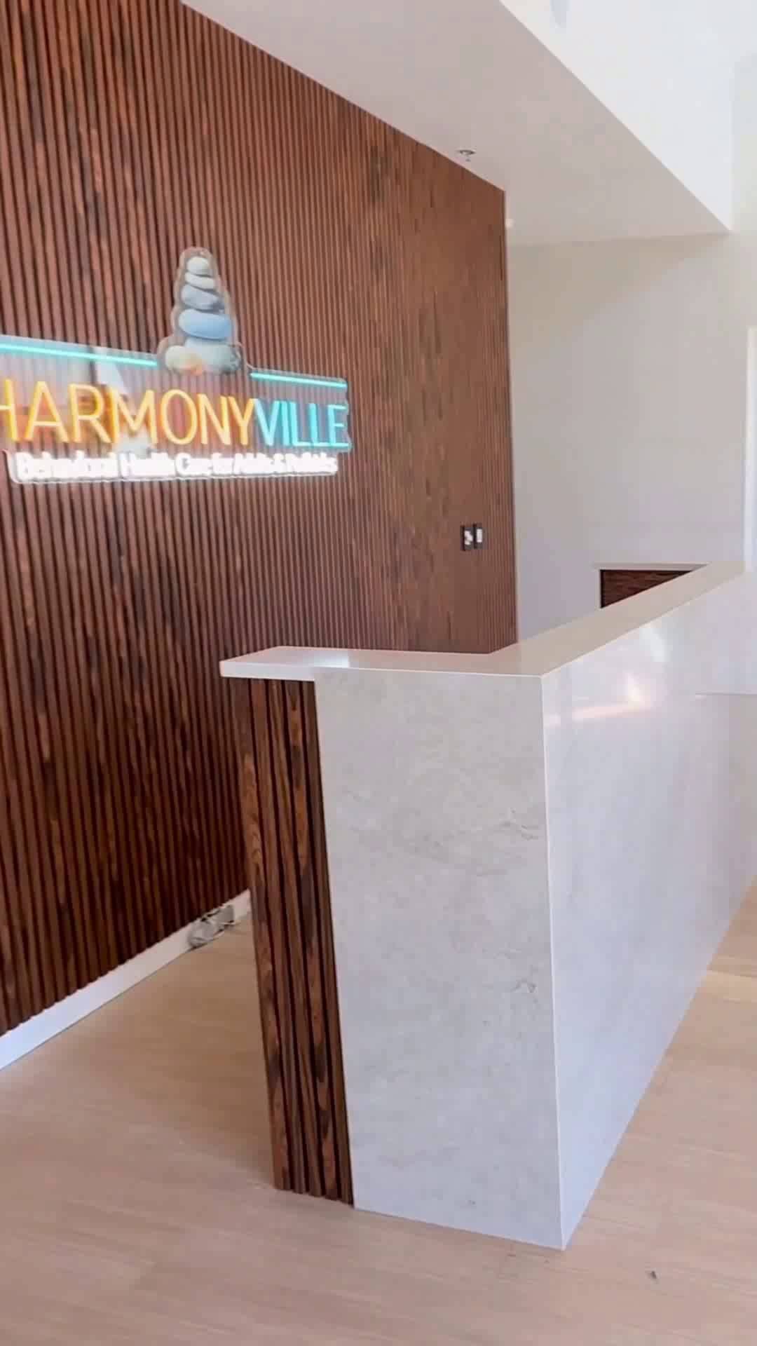 Finished tenant-improvement office reception by i30 Builders: a marble reception desk and walnut slat feature wall with illuminated brand signage.