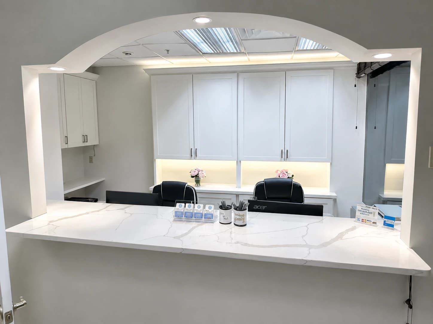 Commercial reception build-out by i30 Builders: Calacatta-faced desk beneath an arched opening
