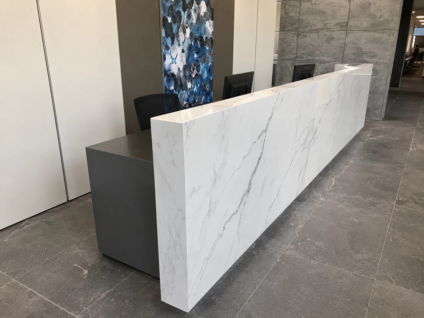 Completed commercial reception build-out with a marble waterfall desk and finished millwork by i30 Builders.