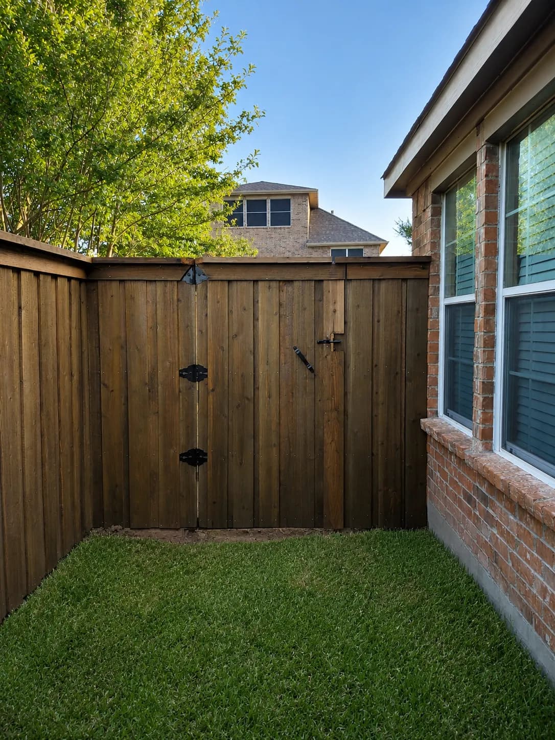 Stained cedar privacy fence with a custom gate on a larger Heath, TX lot by i30 Builders