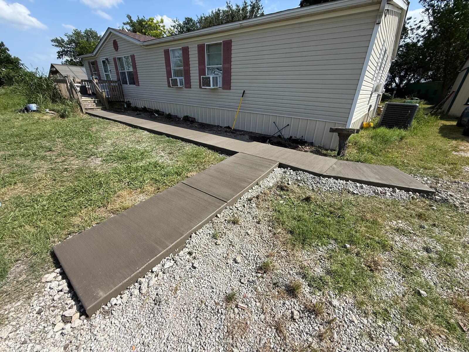 Finished 50 ft concrete walkway alongside a Caddo Mills home with new landscape bed