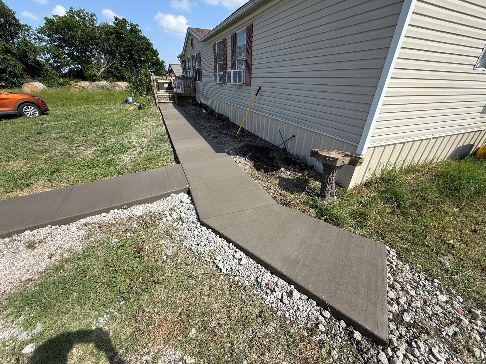 Long 50 ft concrete walkway with broom finish running alongside a Caddo Mills home