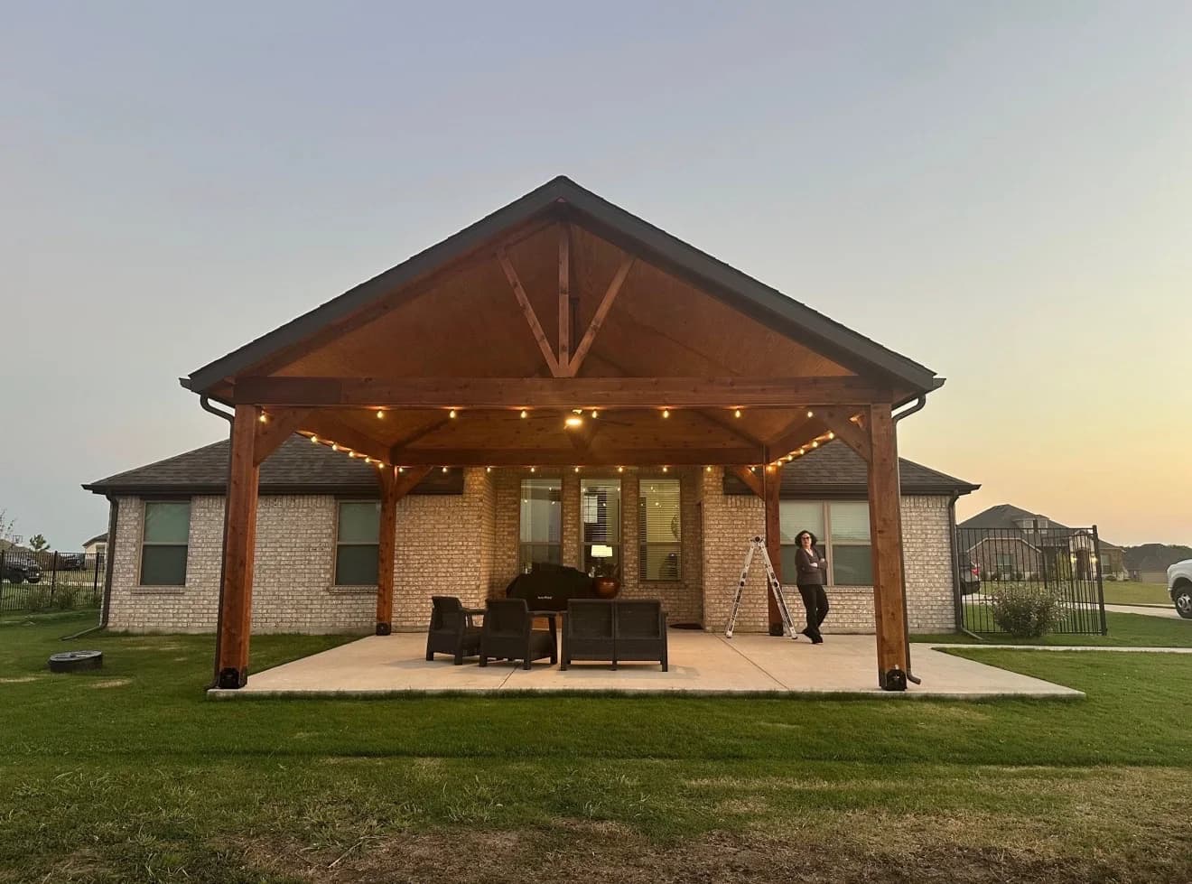 Free-standing cedar pergola with integrated café lighting over a backyard patio in Forney.