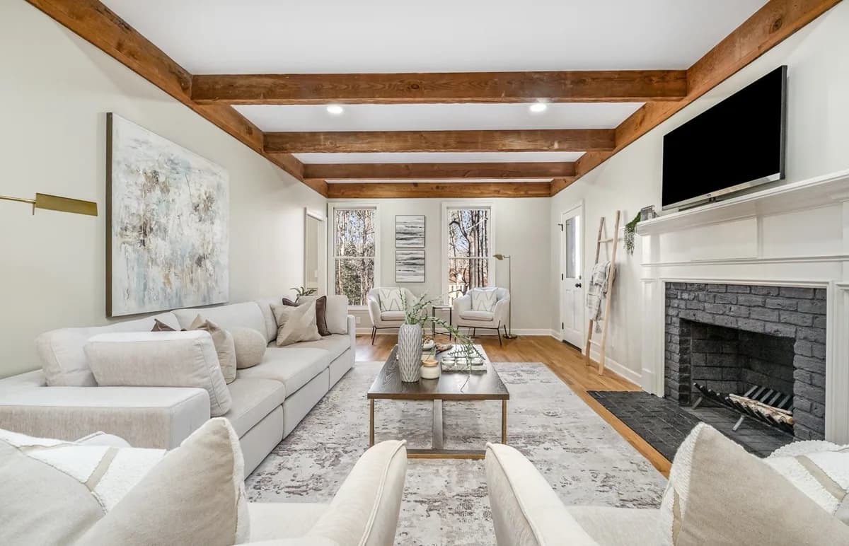 A living room with stained cedar ceiling beams and a painted brick fireplace.