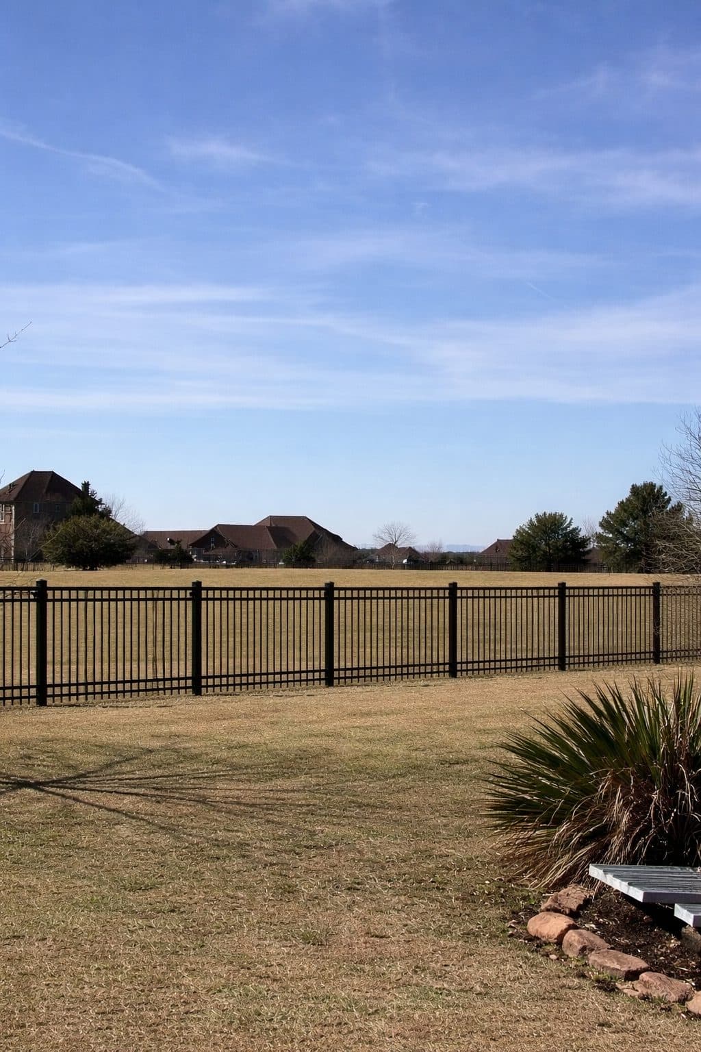 Black metal picket fence along the edge of an open field.