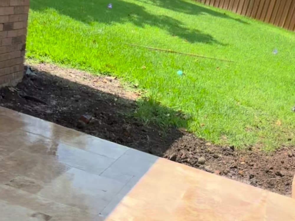 Where the travertine meets the lawn, freshly sealed.
