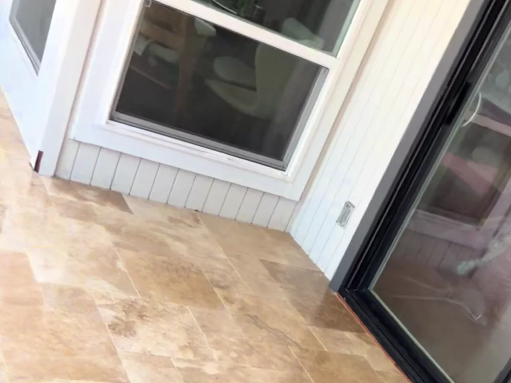 Travertine field set against the siding and the sliding door threshold.