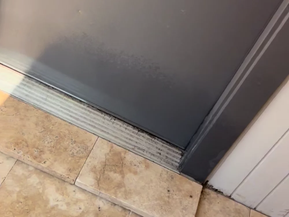 Travertine step tread cut tight to a rear door threshold.