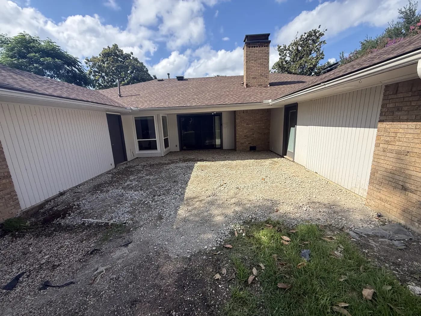 Before: the same Dallas courtyard as a bare gravel base between the brick and siding.