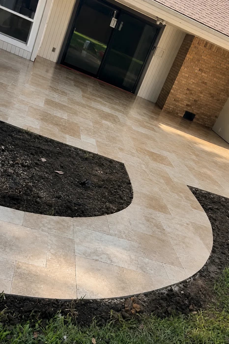 French-pattern travertine courtyard with a curved edge into a planting bed, Dallas.