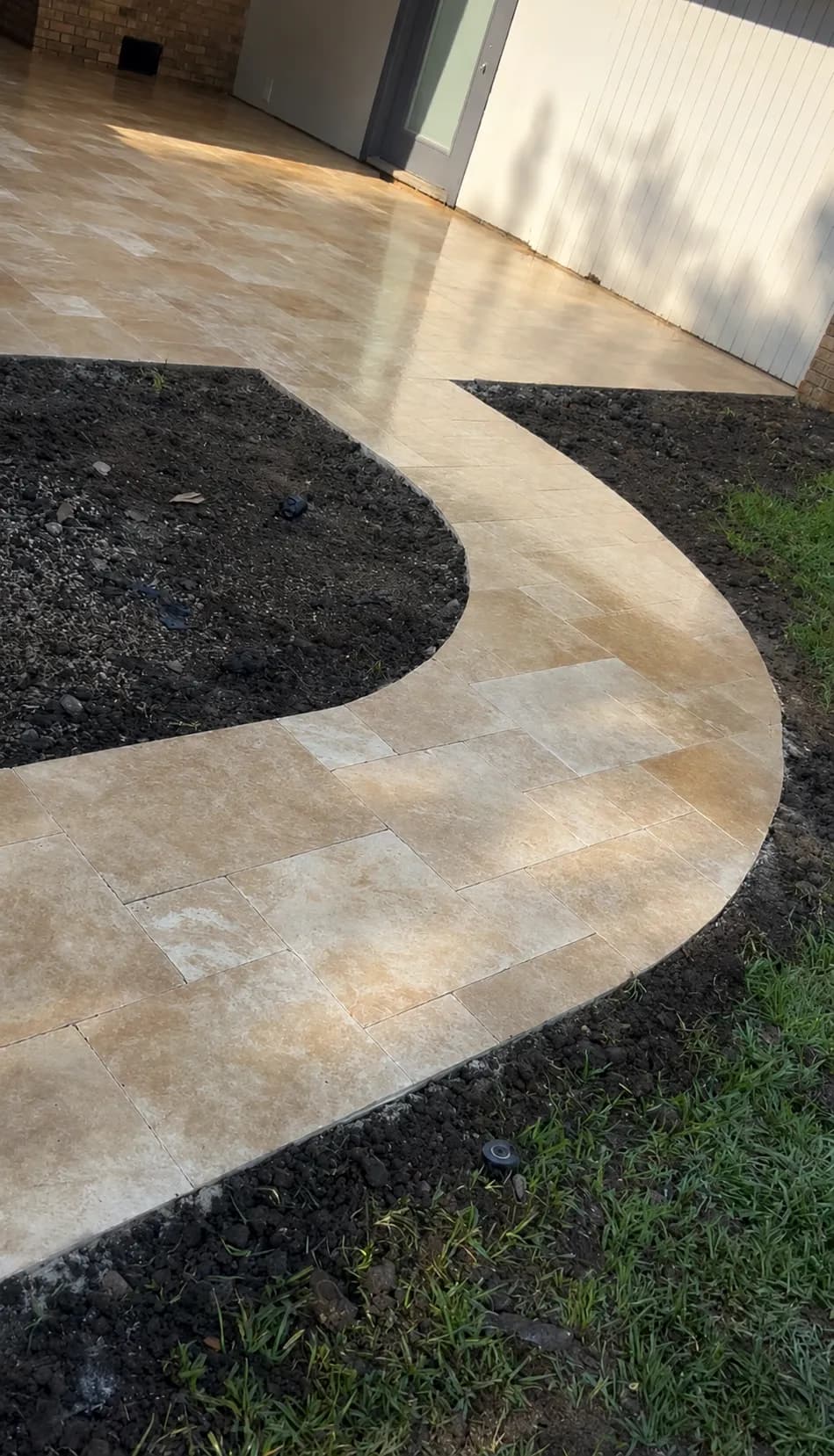 Travertine walkway curving from the courtyard toward the driveway.